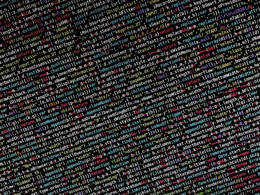 Close-up view of a computer screen displaying lines of programming code with syntax highlighting in various colors, including green, blue, purple, and white. The code appears to be part of a software